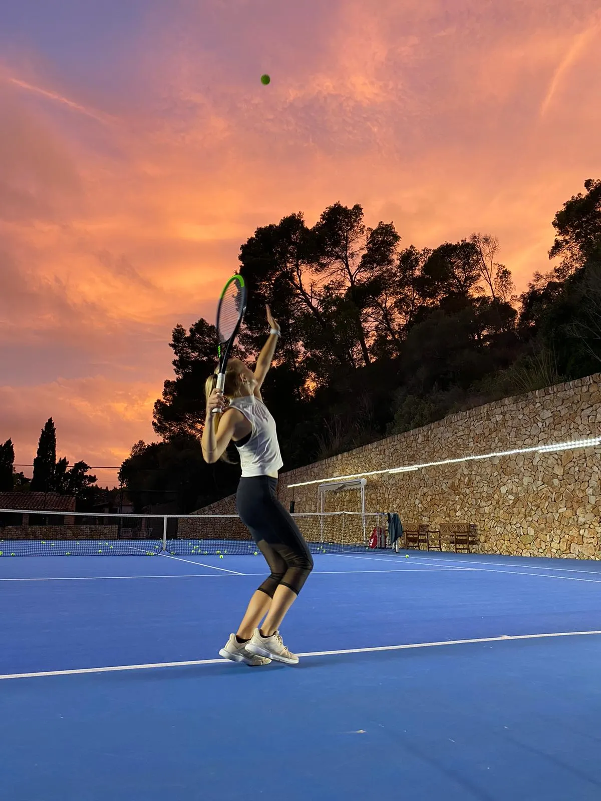 Joueuse au service sur le court, au coucher du soleil